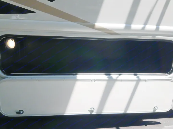 An RV rental's side storage compartment is open, showing a deep, dark interior with an illuminating light.. Thor Four Winds 2020