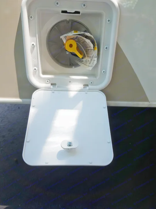 Open utility compartment on an RV rental, revealing a yellow handle and paperwork.. Thor Four Winds 2020