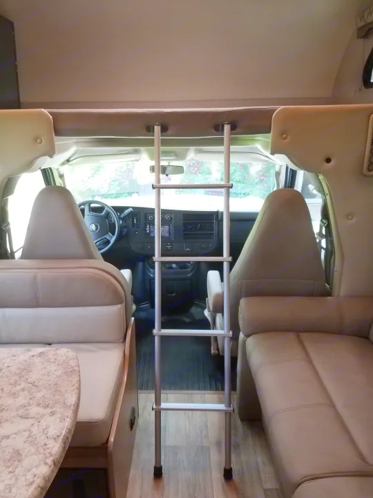 Experience comfort in this RV rental interior, featuring an overhead bunk ladder, driver's cabin, dinette, and sofa.. Thor Four Winds 2020
