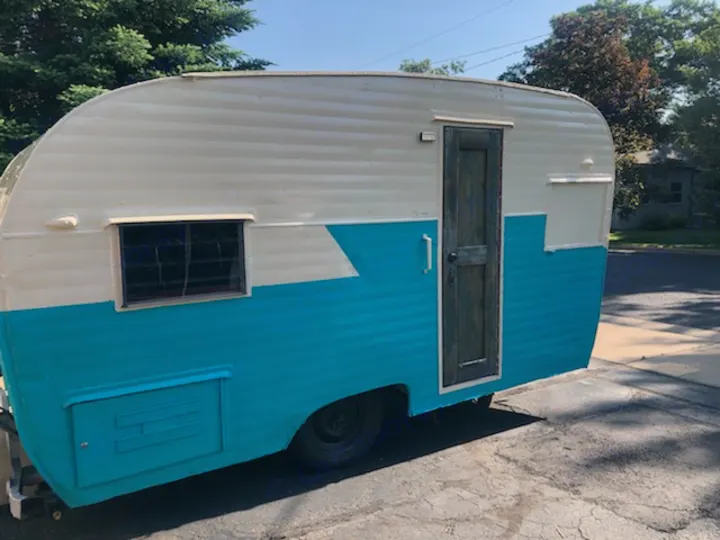 Vintage teal and white camper, ready for your next rv rental. Features side window, door, and exterior storage.. Nomad Rear fold 1962