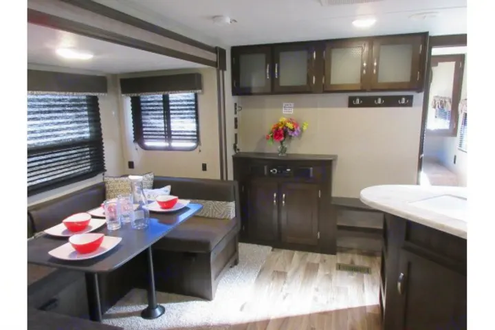 This RV rental interior offers a comfortable living space with a set dinette, entertainment center, and ample storage.. Keystone Springdale 2020