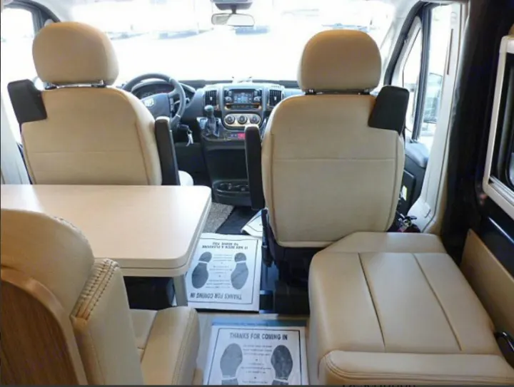 RV rental interior: Swiveled front seats face a table and rear seating, creating a cozy camper van living area.. Winnebago Travato 2020