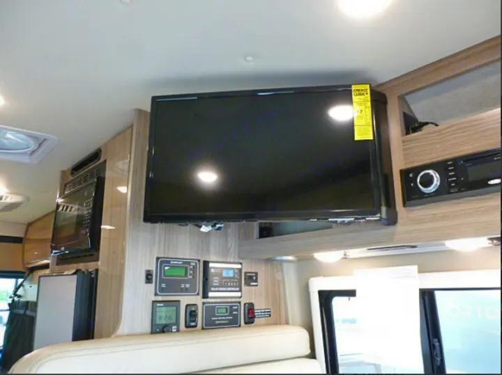 RV rental interior: cozy living space with mounted TV, microwave, system control panels, and entertainment unit.. Winnebago Travato 2020