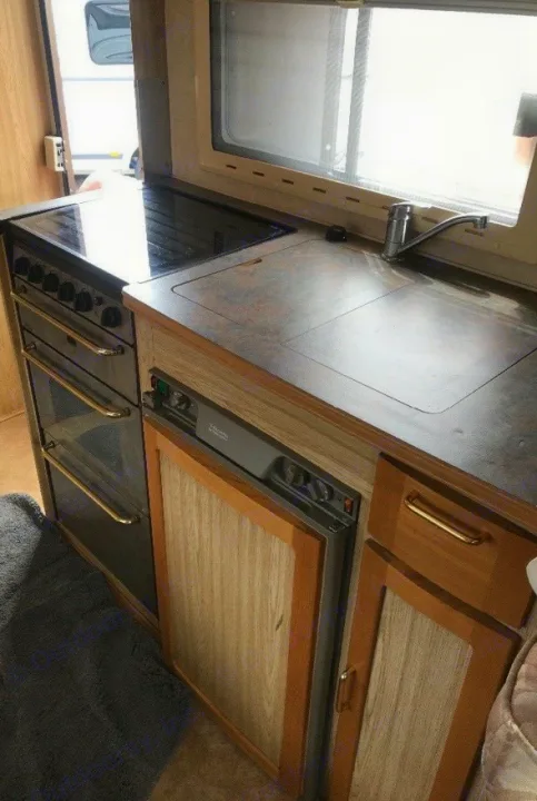 Inside an RV rental: a compact kitchen featuring an oven, stovetop, sink, and integrated refrigerator.. Peugeot Boxer Elddis Auto Stratus EB 1999