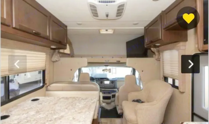 Bright RV rental interior. Shows dining table, armchair, and the motorhome's front cabin. Perfect for travel adventures.. Thor Freedom Elite 2018