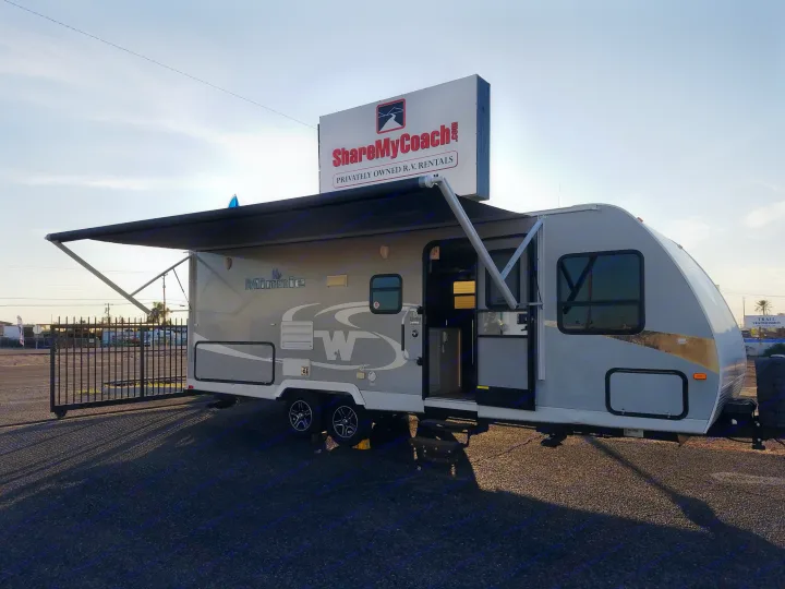 Gray Winnebago RV rental with an extended awning, open door, and a "ShareMyCoach" sign on top.. Winnebago Minnie Winnie 2015