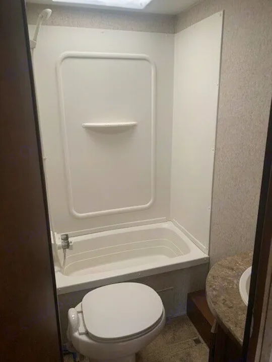 RV rental's functional bathroom: compact tub/shower, toilet, and vanity sink visible. Ready for your travels!. Heartland Prowler 2012