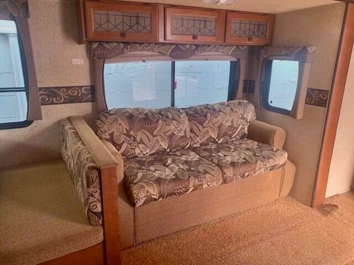 RV rental: Cozy interior featuring a patterned sofa, windows, and overhead storage cabinets.. Heartland Prowler 2012