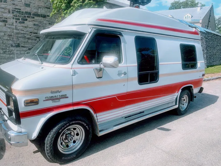 Classic white Chevrolet G10 conversion van with red/tan stripes, ideal for an RV rental adventure or retro road trip.. Chevrolet G20 1983