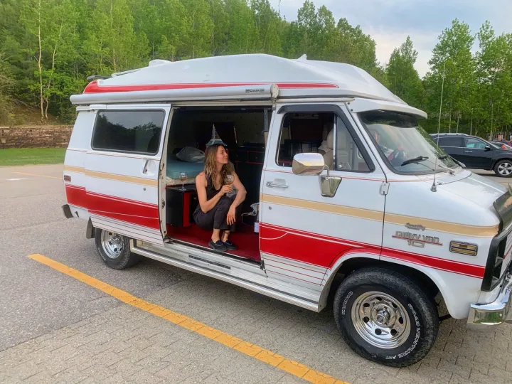 Woman sips wine in a classic Chevy camper van. Explore with an RV rental adventure!. Chevrolet G20 1983