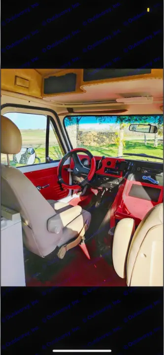 Step inside this cozy rv rental! Customized van interior with red dashboard, tan driver's seat, and scenic countryside view.. Chevrolet G20 1983