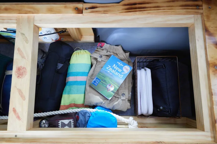 Inside an RV rental: travel essentials like a New Zealand guide, sunscreen, and gear, neatly organized for adventure.. Toyota Voxy 2004