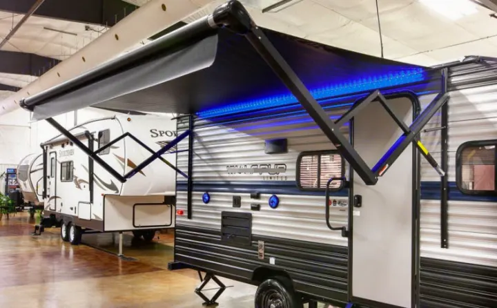 An RV rental travel trailer with a modern, illuminated awning and blue LED lights, displayed indoors.. Forest River Cherokee Wolf Pup 2019