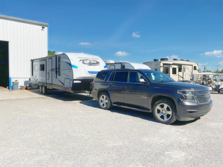 A dark SUV tows an Alpha Wolf Cherokee travel trailer in a lot, perfect for your next rv rental.. Forest River Cherokee Alpha Wolf 2021