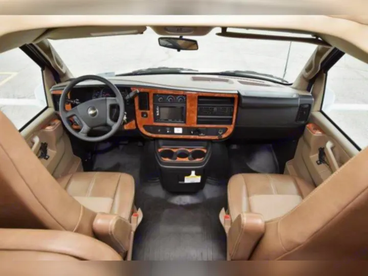 View inside an RV rental showing the driver's area with a Chevrolet steering wheel, wood-trim dashboard, and tan seats.. Thor Quantum 2020