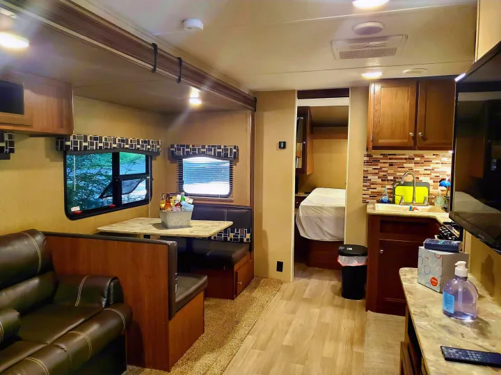 Spacious RV rental interior with a cozy living area, dinette, kitchen, and visible bedroom, perfect for a comfortable trip.. Coleman 285bh 2017