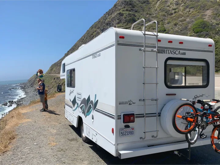 Scenic **rv rental** stop on the California coast. Family enjoys ocean views from their parked RV, bikes ready.. Itasca Spirit 1999