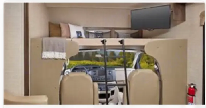 Spacious RV rental interior with a cozy cab-over bunk, TV, and ladder, offering a scenic view.. Jayco Redhawk 2020