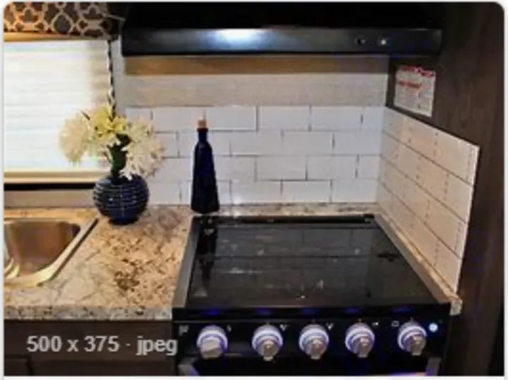 RV rental kitchen featuring a sleek black cooktop, sink, and stylish white tiled backsplash.. Jayco Redhawk 2020