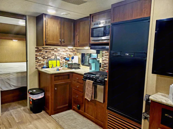 This RV rental offers a well-equipped kitchen with a stove, microwave, and fridge, plus a cozy bedroom area.. Coleman 285bh 2017