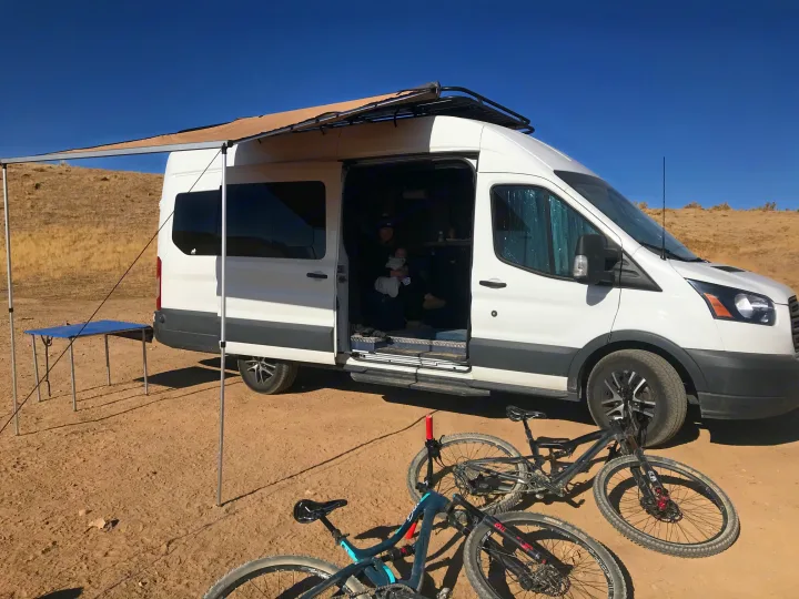 **RV rental** fun: A converted van with an awning, family, and bikes for outdoor adventures in the desert. Perfect for van life camping.. Ford Transit Custom 2015