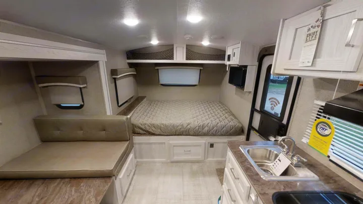 Inside a bright RV rental: features a comfortable bed, compact kitchen, and lounge area for travel.. Forest River Rockwood Geo Pro 2021