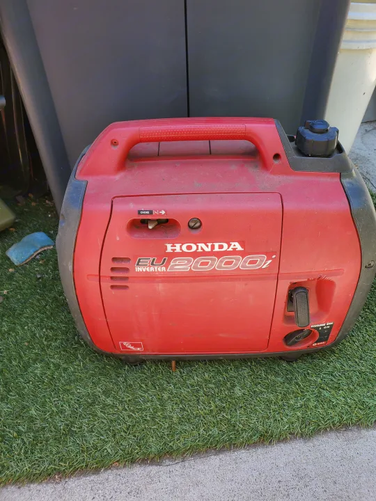 Red Honda EU2000i inverter generator, perfect for RV rental trips and camping. Provides portable power off-grid.. Carson Trailer Toy Hauler 2007