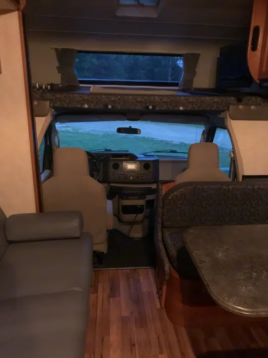 RV rental interior: front cockpit, dinette, and lounge area with wood floors. Ideal for travel adventures.. Coachmen Freelander 2012