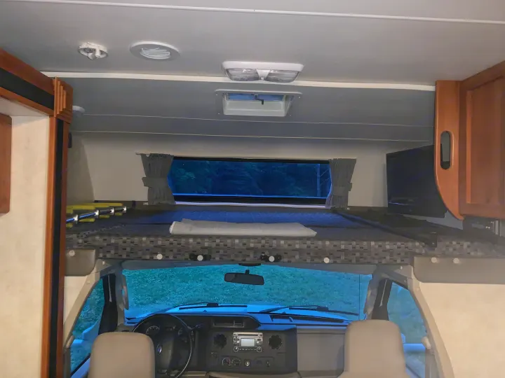Interior view of an RV rental, showing the overhead bunk, rear window, and front cockpit, ideal for travel.. Coachmen Freelander 2012