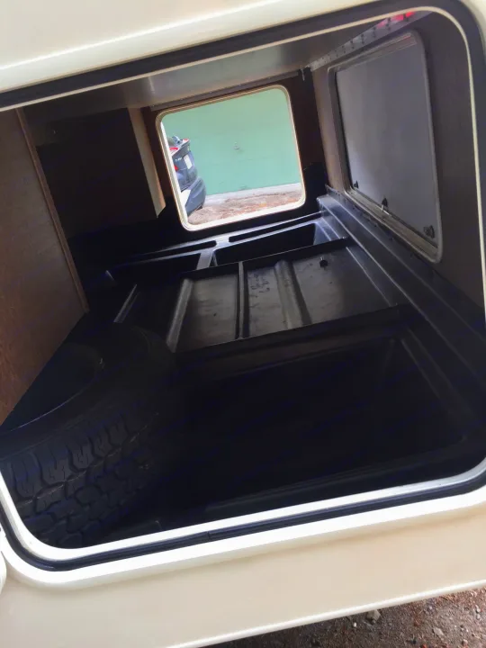 Spacious RV rental exterior storage compartment shows molded floor and a visible spare tire.. Coachmen Freelander 2014