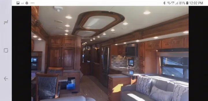 Spacious, luxurious rv rental interior with gleaming wood finishes, a complete kitchen, dining area, and cozy living space.. American Coach 42B 2019
