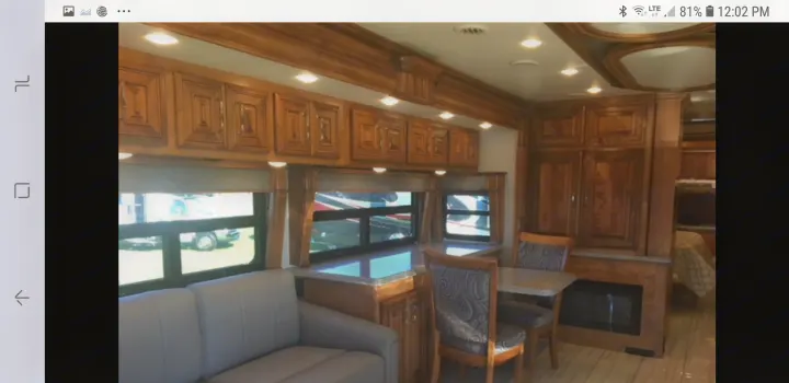 Inside a luxury RV rental: wood cabinets, sofa, dining table, and cozy fireplace creating a welcoming living space.. American Coach 42B 2019