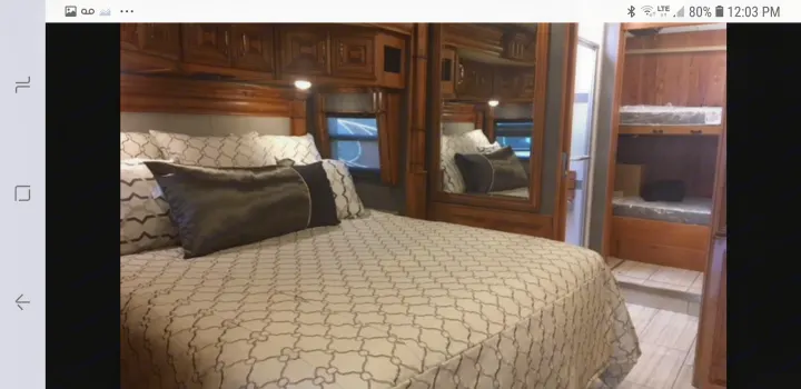 Luxurious RV rental interior featuring a master bed with ornate cabinetry and bunk beds, offering comfort for your journey.. American Coach 42B 2019