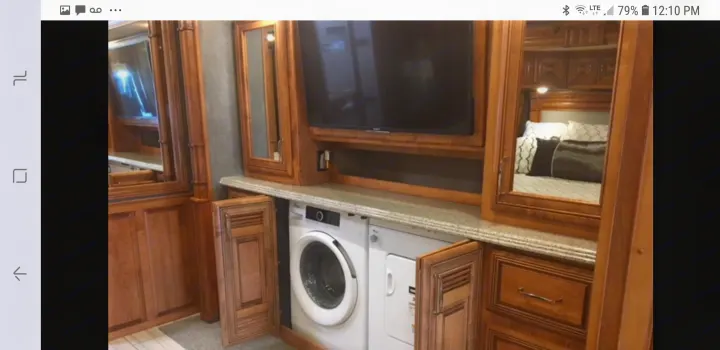 This RV rental boasts a compact washer/dryer, TV, and mirrored view of the bedroom, offering home comforts.. American Coach 42B 2019