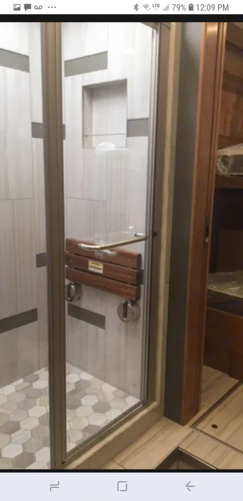 RV rental: well-designed shower with folding seat & tiled walls. Hexagonal floor. Bunk beds seen beyond.. American Coach 42B 2019