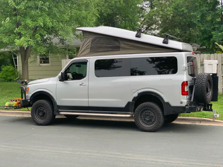 Light gray Nissan NV van converted into an overland camper with a pop-top and rugged tires. Great for rv rental.. Roadtrek N6-Active 2013