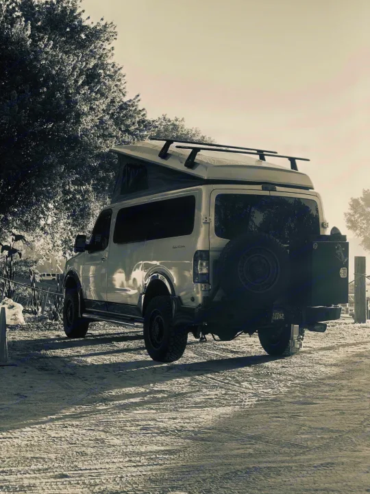 This rugged pop-top camper van, an ideal RV rental, is seen in black and white on a dirt road, equipped for adventure.. Roadtrek N6-Active 2013