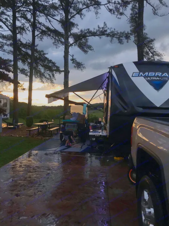 Peaceful RV rental evening at a wet campground site. Travel trailer, truck, and sunset through trees.. Other Other 2018