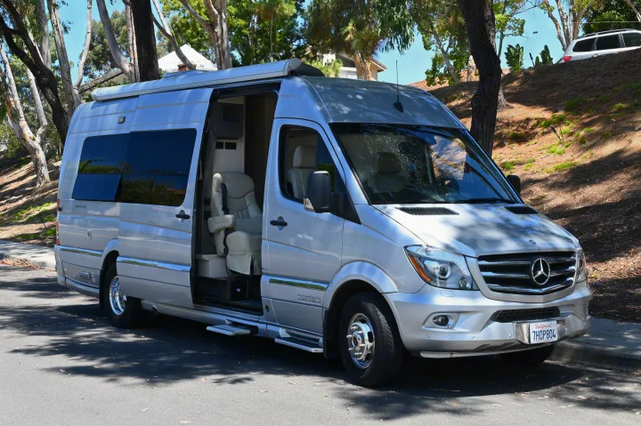 Silver Airstream RV rental, a Mercedes Sprinter camper van, parked with its side door open.. Airstream Airstream 2014