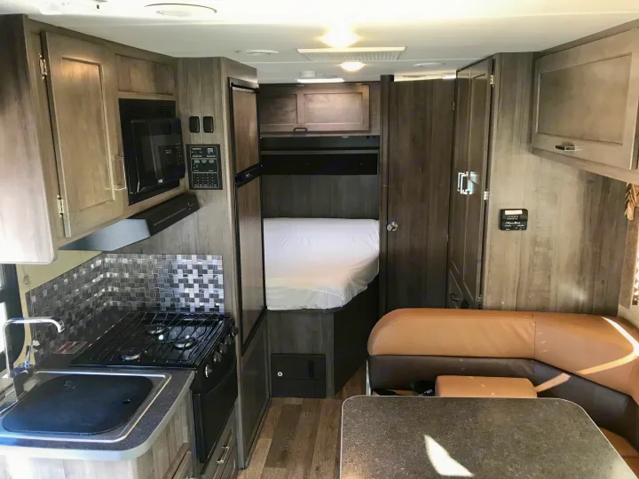 Spacious RV rental interior featuring a kitchen, cozy bed, and dining area. Ideal for your next road trip adventure.. Winnebago Minnie Winnie 2019