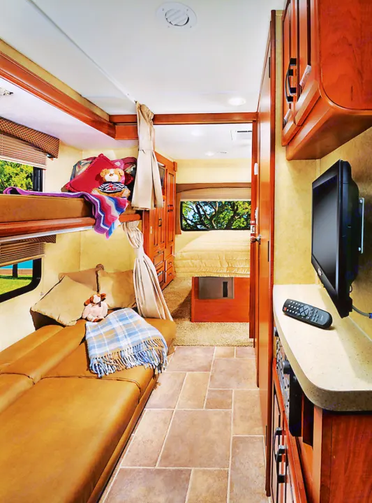Comfortable rv rental interior featuring bunk beds, a master bed, and cozy living area. Ideal for family adventures.. Forest River Sunseeker LE 2015