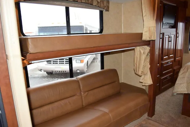 RV rental interior: Features comfy bunk beds above a leather sofa, with built-in storage and TV. Spacious living area.. Forest River Sunseeker LE 2015
