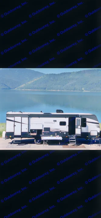 Hideout RV rental set up for lakeside camping with mountain views and outdoor living.. Keystone Bunkhouse 2020