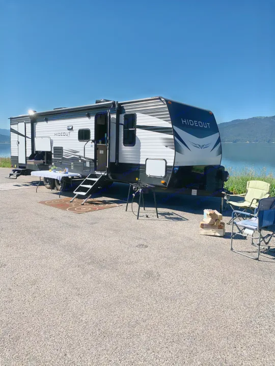 Spacious Hideout RV rental parked lakeside, complete with outdoor cooking & seating for a relaxing camp.. Keystone Bunkhouse 2020