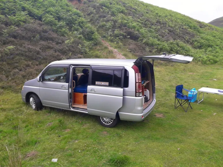 This silver campervan rv rental, set up for cozy van life and outdoor camping, offers adventure amidst nature's beauty.. honda stepwagon 2022