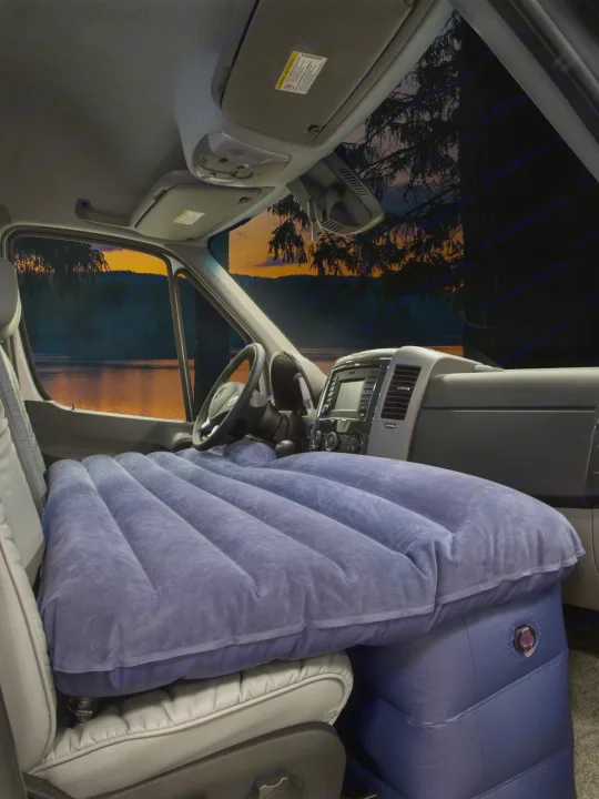 Inside an RV rental van, a blue inflatable air mattress creates a comfortable bed. Enjoy the sunset lake view!. Roadtrek Ssagile 2014