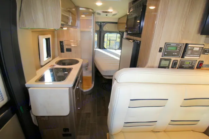 Inside an RV rental: compact kitchen, bed, and bath area. Fully equipped camper van interior ready for adventure.. Winnebago Travato 2020