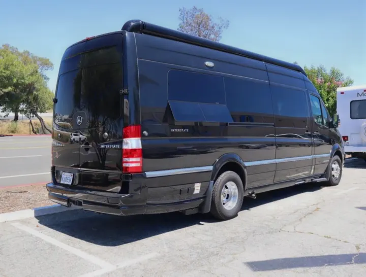 Black Airstream Interstate, a luxury Mercedes-Benz Sprinter RV rental, parked on a sunny day. Rear and side view of the camper van.. Airstream Interstate 2019