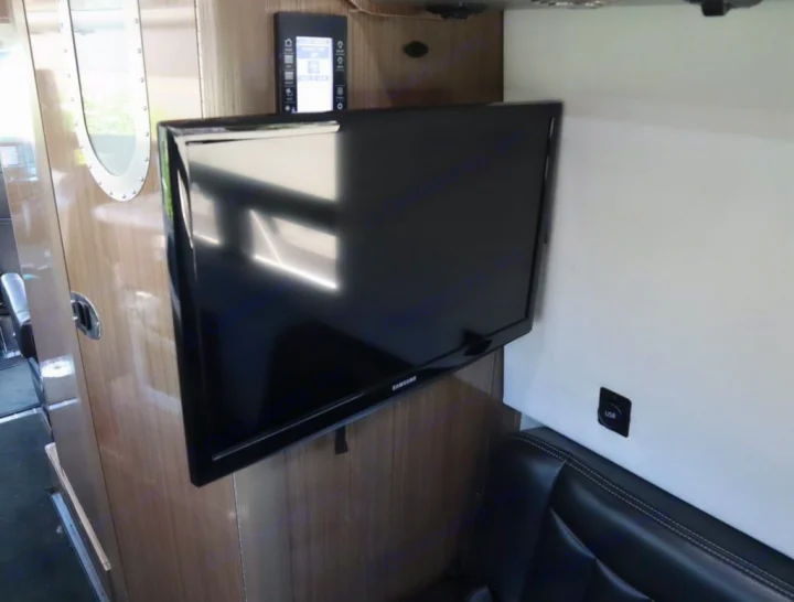 RV rental interior features a mounted Samsung TV, control panel, USB port, and comfortable seating for entertainment.. Airstream Interstate 2019