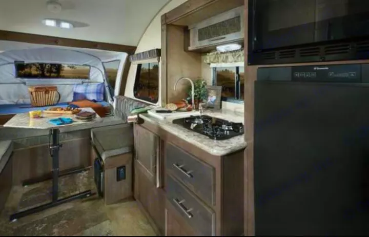 Inside an RV rental: compact kitchen with sink/stove, dining area, and spacious pop-out sleeping/lounge space. Ideal for trips.. Other Other 2016